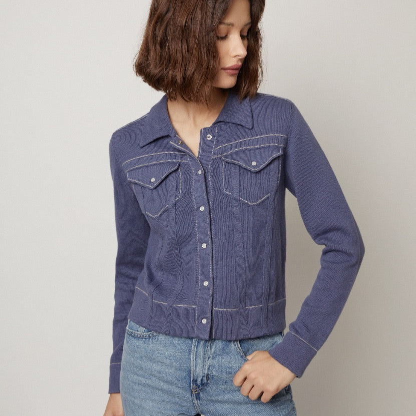 Woman wearing a blue denim jacket and jeans against a plain background
